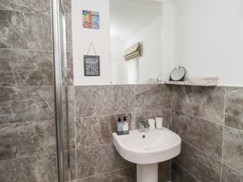 A bathroom with a pedestal sink a large mirror stone tiled walls and small wall decorations at Coastal Retreat in Seahouses