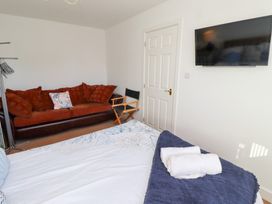 A bedroom with a bed a brown sofa a director chair a wall-mounted television and folded towels on the bed at Coastal Retreat in Seahouses