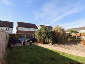 A backyard garden with grass, patio furniture, plants, and a clothesline at Coastal Retreat in Seahouses