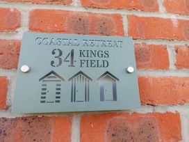 A house number plaque reading Coastal Retreat 34 Kings Field mounted on a brick wall