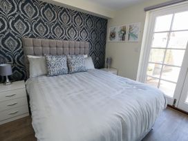 A bedroom with a bed, bedside table, lamp, and artwork at Apartment 1 in Weymouth