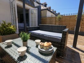 An outdoor seating area with a sofa, table, cups, and muffins at Apartment 1 in Weymouth