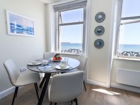A dining room with a table and chairs overlooking the sea at Apartment 2 in Weymouth