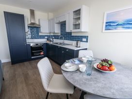 A kitchen with blue cabinets and a dining table at Apartment 2 Weymouth