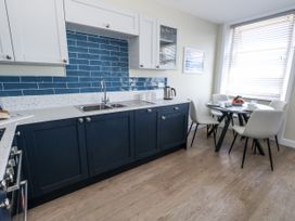 A kitchen with cabinets and a dining table at Apartment 2 in Weymouth