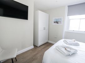 A bedroom with a bed, wardrobe, television, and a chair at Vista Mare 2 in Weymouth
