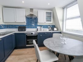 A kitchen with blue cabinets and a round table at Vista Mare 3 Weymouth