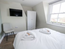 A bedroom with a bed, wardrobe, chair, and television at Vista Mare 3 in Weymouth