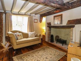 A sitting room with a sofa cushions fireplace and wooden beams at Thatch Cottage in Trunch