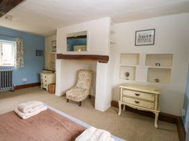 A bedroom with a bed with folded towels a floral armchair a decorative chest of drawers and built in shelves at Thatch Cottage in Trunch