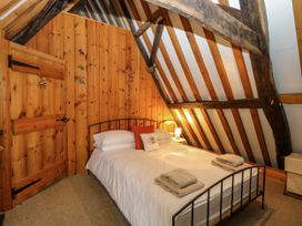 A bedroom with a double bed towels on the bed and wooden walls and ceiling beams at Thatch Cottage in Trunch
