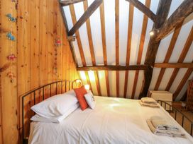 A bed with white linens and pillows in a bedroom with wooden walls and exposed ceiling beams at Thatch Cottage in Trunch