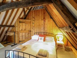 A bedroom with a double bed bedside chair wooden walls and exposed beams at Thatch Cottage in Trunch