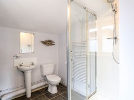A bathroom with a sink toilet mirror shower and decorative fish wall art at Thatch Cottage in Trunch