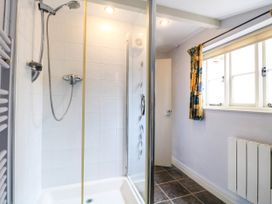 A bathroom with a shower cubicle a window with curtain and a radiator at Thatch Cottage in Trunch