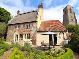 An outdoor area with a table and chairs at Thatch Cottage in Trunch