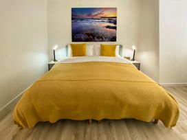 A bedroom with a bed and wall art at Sandwood Studios in Crantock