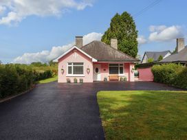 A pink house with a driveway and lawn at Rosemont in Adare