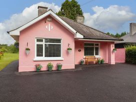 A house with a pink exterior and a bench outside at Rosemont in Adare