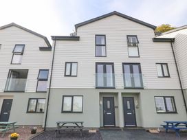 A three-story residential building with dark doors two picnic tables and potted plants at 3 Yr Hen Lys in Pwllheli
