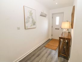 A hallway with a front door a wooden table with a lamp a wall shelf with hooks and a map at 3 Yr Hen Lys in Pwllheli