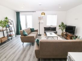 A living room with two brown sofas a coffee table a TV on a wooden stand and plants at 3 Yr Hen Lys in Pwllheli