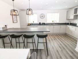 A kitchen with a peninsula and black bar stools at 3 Yr Hen Lys in Pwllheli