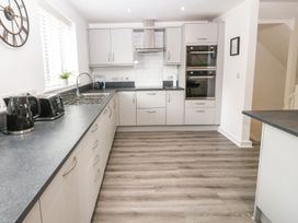 A kitchen with white cabinets black countertop double ovens and black appliances at 3 Yr Hen Lys in Pwllheli