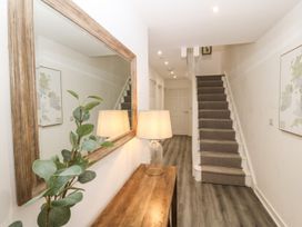 A hallway with stairs and a wooden table holding a lamp and plant at 3 Yr Hen Lys in Pwllheli