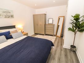 A bedroom with a bed a wardrobe chest of drawers a standing mirror a lamp and a potted plant at 3 Yr Hen Lys in Pwllheli