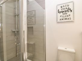 A bathroom with a glass shower enclosure and a toilet with a sign above at 3 Yr Hen Lys in Pwllheli