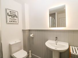 A bathroom with a toilet sink mirror and a framed sign on the wall at 3 Yr Hen Lys in Pwllheli