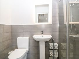 A bathroom with a toilet a pedestal sink a small mirror and a shower enclosure at 3 Yr Hen Lys in Pwllheli