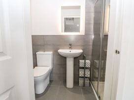 A bathroom with a toilet sink mirror and shower at 3 Yr Hen Lys in Pwllheli