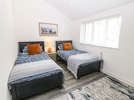 A bedroom with two single beds a nightstand and a window at 3 Yr Hen Lys in Pwllheli