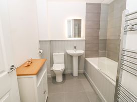 A bathroom with a toilet sink bathtub mirror and towel rack at 3 Yr Hen Lys in Pwllheli
