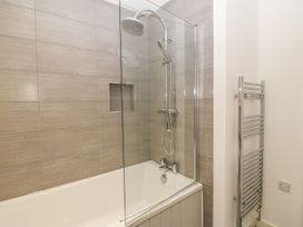 A bathroom with a bathtub shower combination and a heated towel rack at 3 Yr Hen Lys in Pwllheli