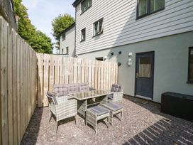 An outdoor patio area with a black door and rattan furniture set including a sofa chairs stools and a glass table at 3 Yr Hen Lys in Pwllheli