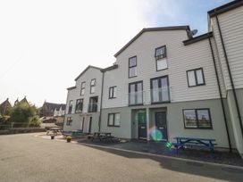 A modern residential building with multiple entrances and outdoor picnic tables at 3 Yr Hen Lys in Pwllheli