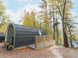 An outdoor pod-style cabin with a small raised deck surrounded by trees at Elleric Pods - The Last Resort in Fasnacloich near Appin