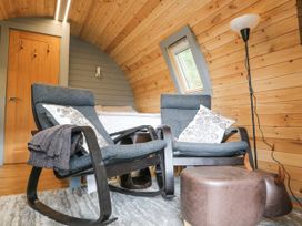 A room with two armchairs and cushions near a bed a window wooden door and a floor lamp at Elleric Pods - The Last Resort Fasnacloich near Appin