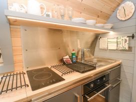 A kitchen counter with a stovetop sink oven dishes and dish rack at Elleric Pods - The Last Resort Fasnacloich near Appin