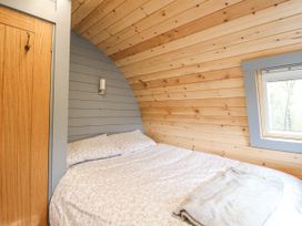 A bedroom with a double bed a wooden door and a window in a wooden pod at Elleric Pods - The Last Resort in Fasnacloich near Appin