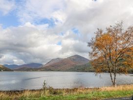 A lake with hills in the background and a tree with orange leaves by the shore at Elleric Pods - The Last Resort in Fasnacloich near Appin
