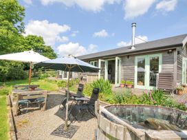 A garden with chairs, table, umbrellas, and hot tub at Smugglers Bodmin Moor, St Breward near St Tudy