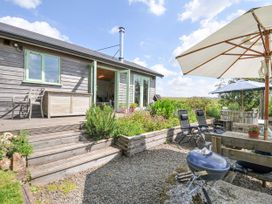 An outdoor area with a deck, table, chairs and barbecue grill at Smugglers, Bodmin Moor, St Breward near St Tudy