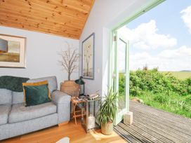A living room with a sofa and door opening to the outside at Smugglers, Bodmin Moor, St Breward near St Tudy