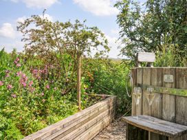 A garden area with a wooden bench and flowers at Smugglers, Bodmin Moor, St Breward near St Tudy