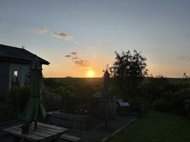 A sunset view from a garden with chairs and a table at Smugglers, Bodmin Moor, St Breward near St Tudy