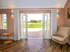 A living room with a chair and table looking out to the garden at Hoddell Pitch Cottage Kinnerton near New Radnor